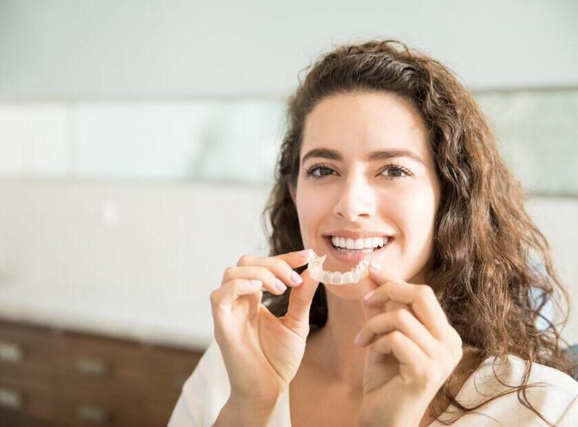 Beautiful Patient Holding Orthodontic Retainers In Dental Clinic